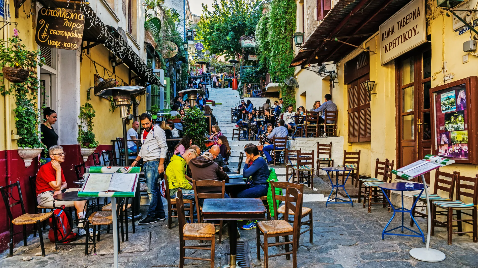 Outdoor taverna seating along a narrow stairway street in the Plaka neighborhood